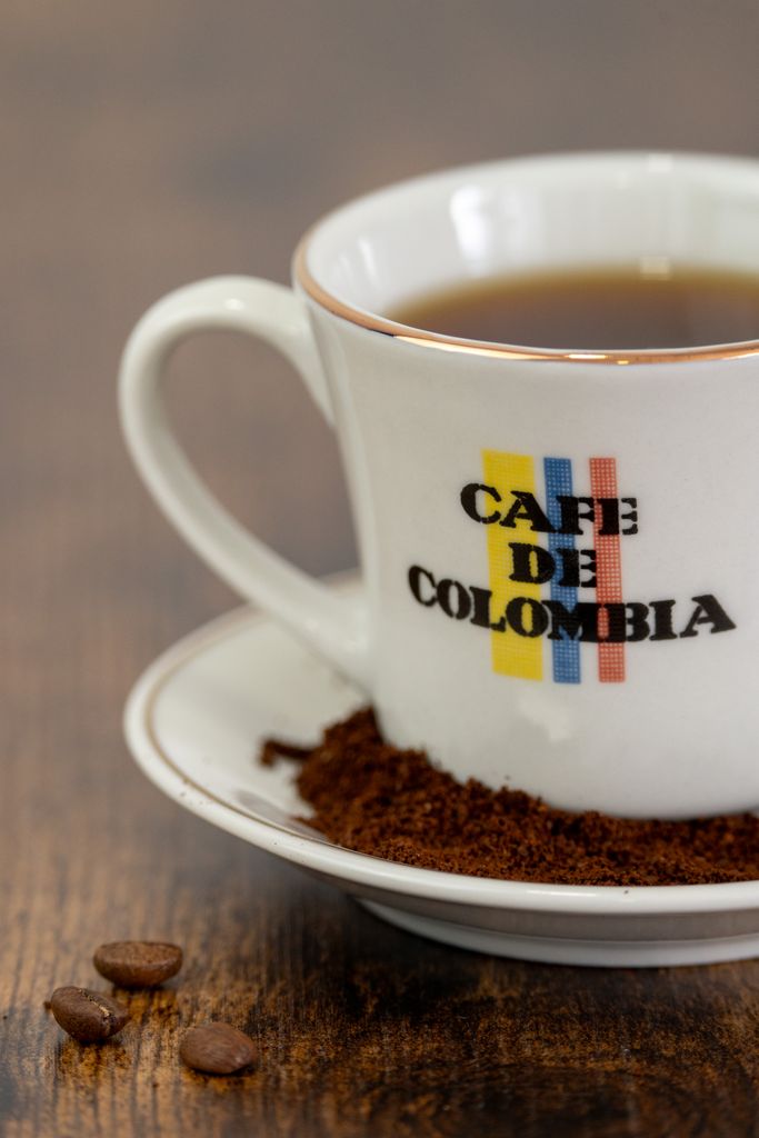 Close-up of a Colombian coffee cup with coffee grounds on a wooden table.